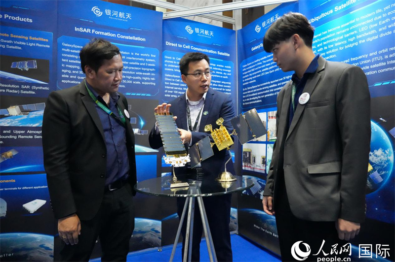 银河航天国际业务拓展总经理黄和平（中）向参观者介绍柔性太阳翼平板卫星技术。人民网记者 简承渊摄