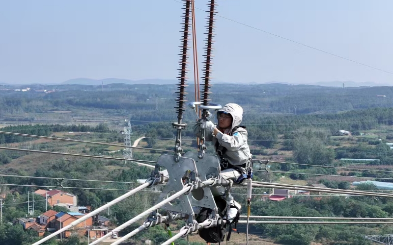 国网湖北电力员工在500千伏桐钟线76号塔作业现场开展绝缘子高压端均压环带电补装紧固工作。程超摄
