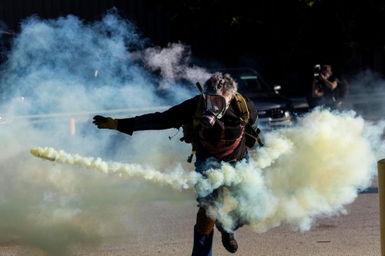 9月26日，在位于美国芝加哥西郊布罗德维尤市的移民与海关执法局办事机构外，抗议者在冲突中将执法人员发射的催泪弹瓶扔回。新华社发（文森特·约翰逊摄）